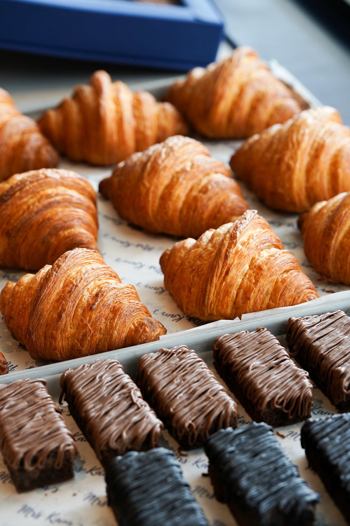 Rows of croissants above milk and dark chocolate brownies on Mrs Kaur’s tissue