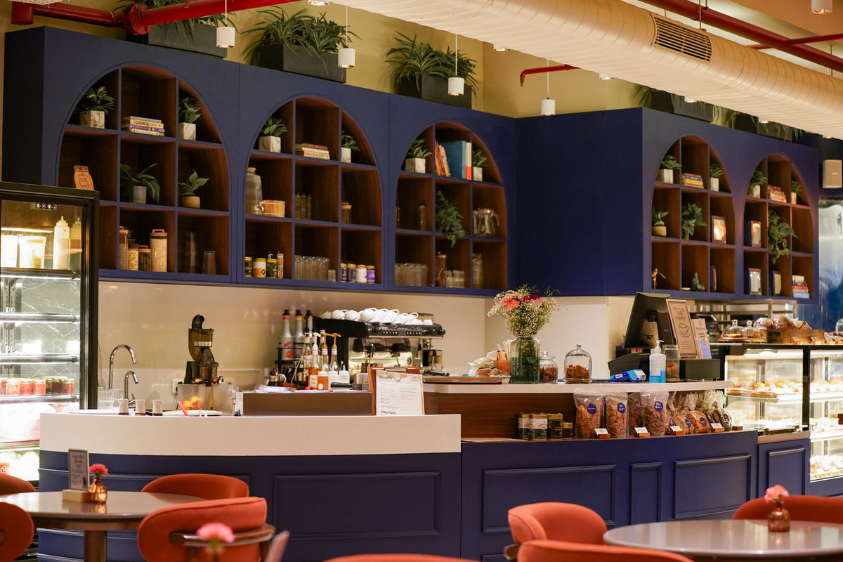 The bakery counter at Mrs Kaur’s, with Oxford Blue arched shelving and terracotta café chairs